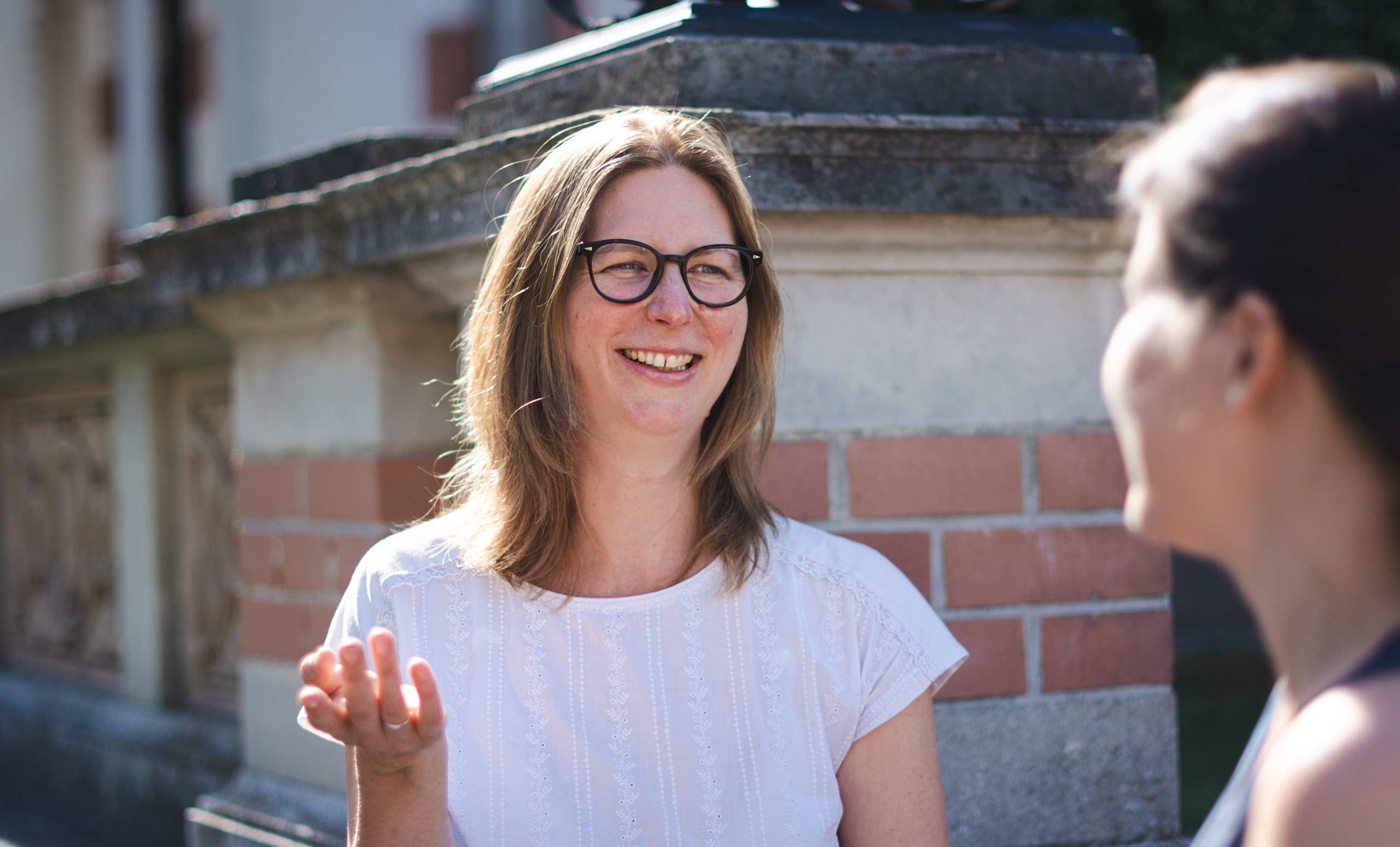 Hanna Scharf lächelt freundlich in die Kamera während sie sich mit einer Klientin unterhält